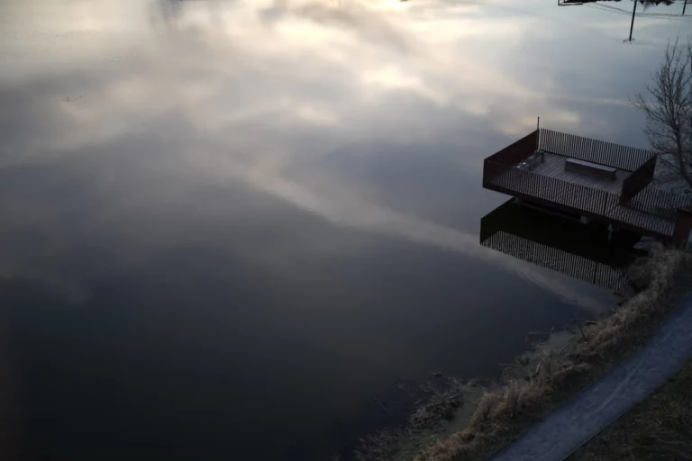 Ponton sur un lac où se reflète un ciel nuageux